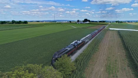 Ronks,-Pennsylvania,-September-4,-2021---Drone-Slightly-Ahead-View-of-a-Steam-Passenger-Train-Traveling-Thru-Farmlands-With-Fields-of-Crops-and-Corn