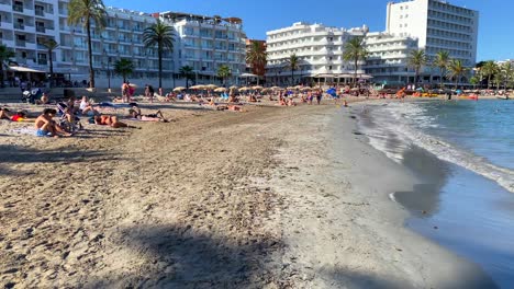 Famoso-Destino-De-Vacaciones-De-Verano-Playa-De-Ses-Figueretes-En-La-Isla-De-Ibiza-España,-Gente-De-Vacaciones,-Hoteles-Y-Apartamentos-En-El-Fondo,-Ciudad-De-Ibiza,-Toma-De-4k