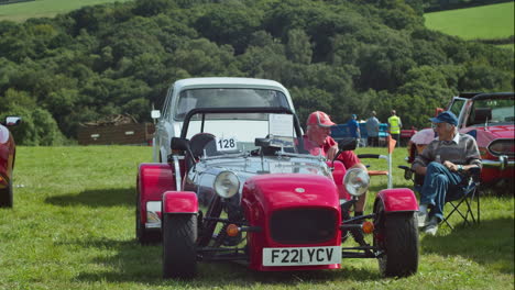 Dos-Ancianos-Sentados-Y-Hablando-Junto-A-Un-Coche-Deportivo-Caterham-Siete-Rojo