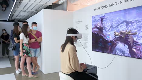 Un-Visitante-De-Arte-Usa-Un-Casco-De-Realidad-Virtual-Para-Interactuar-Con-Una-Obra-De-Arte-Inmersiva-Mientras-Otros-Entusiastas-Y-Asistentes-Hacen-Cola-En-La-Feria-De-Arte-Digital-Que-Muestra-Las-Próximas-Tendencias