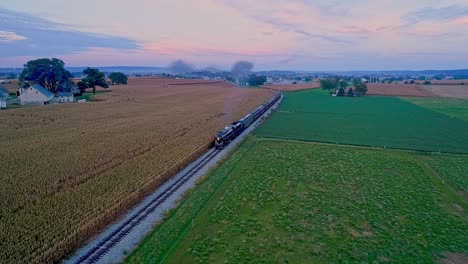 Ronks,-Pennsylvania,-October-2,-2021---Drone-Slightly-Ahead-View-of-a-Steam-Passenger-Train-Traveling-Thru-Farmlands-With-Fields-of-Crops-and-Corn