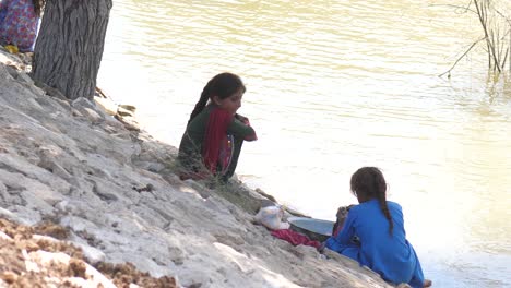 Niña-Lavando-La-Ropa-Junto-Al-Río-En-Maher,-Sindh