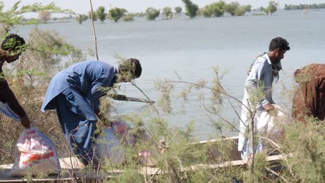 Locals-Helping-With-Aid-Lifting-Onto-Boat-Beside-River-In-Sindh-For-Flood-Relief-In-Maher-In-Sindh