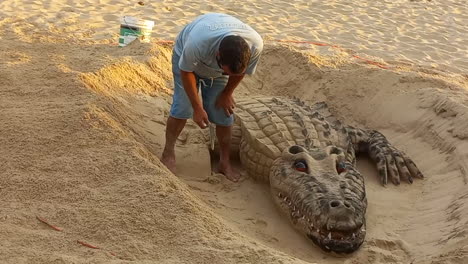 Mann-Macht-Eine-Skulptur-Eines-Sandkrokodils-Am-Strand,-Sehr-Schön