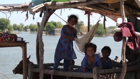 Video-of-two-small-girl-and-other-children-are-standing-in-the-khatiya-inside-the-poorly-made-tent-looking-directly-at-the-camera-in-Maher,-Sindh