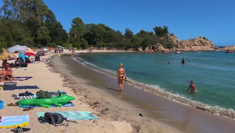 Gente-De-Vacaciones-Caminando-En-La-Orilla-Y-Bañándose-En-Aguas-Cristalinas-De-Color-Turquesa-De-La-Idílica-Playa-De-Canella-En-La-Isla-De-Córcega,-Francia