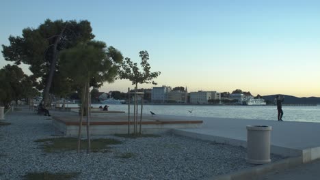 Establisher-view-of-Zadar-old-town,-people-photographing-and-admiring-sunset,-Croatia