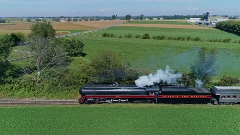 Ronks,-Pennsylvania,-September-25,-2021---Drone-Side-View-of-a-Steam-Locomotive-Traveling-on-a-Single-Track-Thru-Farmlands,-Blowing-Smoke