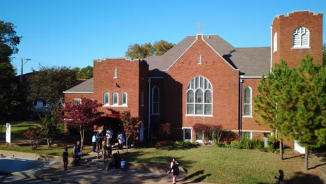 Establishing-aerial-drone-shot-of-people-leaving-a-stunning-church