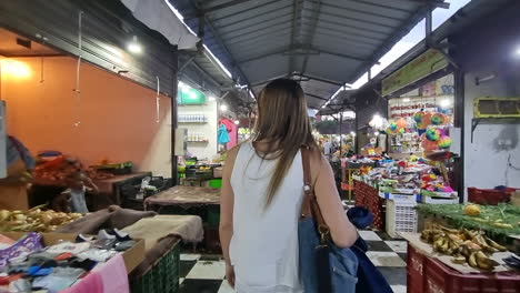 Foto-De-Una-Mujer-Caminando-Por-Las-Calles-De-La-Ciudad-De-Ayoun,-Donde-Se-Pueden-Ver-Tiendas-De-Ropa-Y-Comida