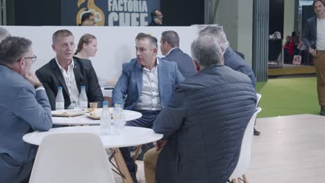 Gruppe-Professioneller-Männer,-Am-Tisch-Sitzend,-Lockere-Diskussion,-Auf-Der-Lebensmittelmesse