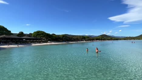 Gente-En-La-Playa-Y-Disfrutando-De-Las-Vacaciones-De-Verano-Bañándose-En-El-Agua-De-Mar-Clara-De-Santa-Giulia-En-La-Isla-De-Córcega-En-Francia