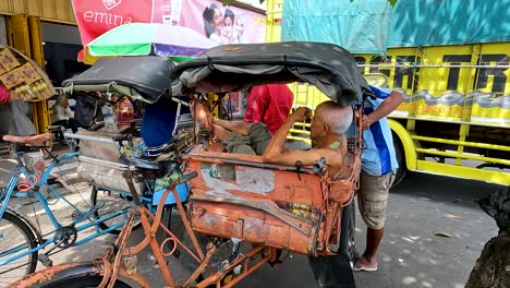 Pedicab-driver-resting-on-trishaw-in-Magelang,-Java,-Indonesia