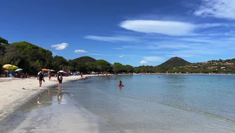 Santa-Giulia-famous-French-Corsican-heavenly-beach-with-crystalline-turquoise-sea-water-and-tourists-on-vacation-walking-on-shore