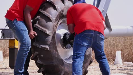 Trabajadores-Conectando-Cuidadosamente-Un-Neumático-Grande-Al-Sistema-De-Riego-De-Pivote-Central-En-Una-Granja-Rural-En-Sindh