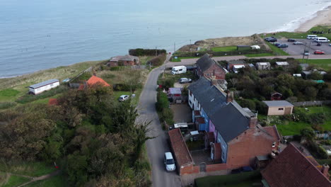 Una-Vista-Aérea-De-La-Carretera-De-La-Playa-Del-Pueblo-De-Happisburgh-Que-Termina-Abruptamente-Debido-Al-Aumento-De-La-Erosión-Costera-Y-Los-Restos-Estructurales-De-Los-Edificios-Antiguos-Se-Asoman-Desde-El-Mar-Del-Norte-En-La-Costa-De-Norfolk