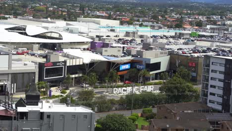 Panning-shot-capturing-the-front-entrance-of-pacific-fairs-shopping-centre-on-Hooker-Blvd,-building-exterior-and-compact-parking-area-on-the-weekend-during-holiday-season,-Broadbeach,-Gold-Coast