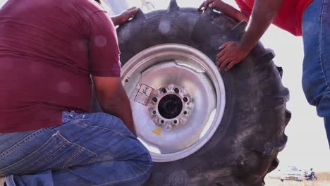 Low-Angle-View-Of-Men-Holding-Large-Tyre-Of-Center-Pivot-Irrigation-System