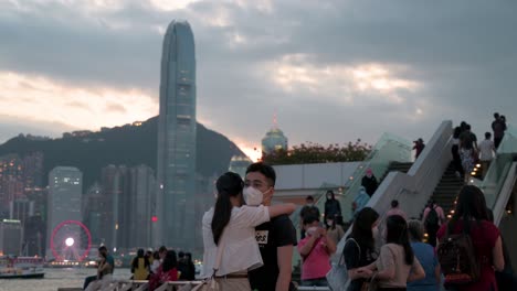 Una-Pareja-Se-Abraza-Y-Muestra-Su-Movimiento-Mientras-Disfrutan-De-La-Vista-De-La-Noche,-La-Puesta-De-Sol-Y-El-Horizonte-De-Los-Rascacielos-De-La-Isla-De-Hong-Kong