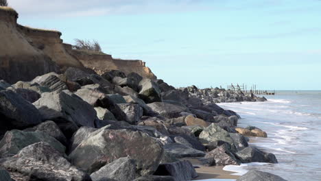 Wellen-Rollen-Von-Der-Nordsee-Auf-Einen-Strand,-Der-Durch-Einen-Meeresschutz-Aus-Granitfelsen-An-Der-Durch-Küstenerosion-Beschädigten-Küste-Von-Norfolk-Geschützt-Ist