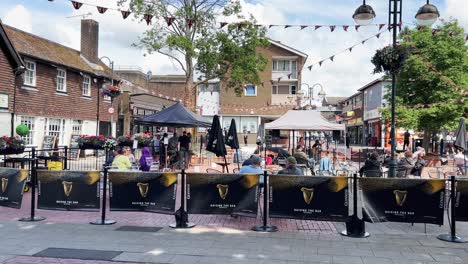 Panning-view-of-Crawley-downtown-square-with-people-enjoying-drinking-beer-outdoors-on-summer-day,-UK