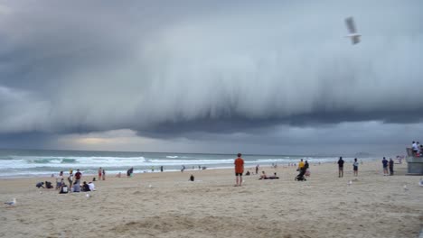 Toma-Panorámica-A-Través-De-La-Playa-Costera-En-El-Paraíso-De-Los-Surfistas,-Gruesa-Capa-De-Ominosas-Nubes-Oscuras-De-Tormenta-Que-Barren-El-Cielo-Con-Viento-Fuerte-Y-Furioso,-Costa-Dorada,-Queensland,-Australia