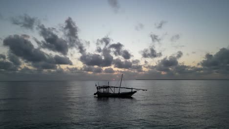 Barco-De-Pesca-Flotando-Cerca-De-La-Orilla-Durante-La-Puesta-De-Sol-Oscura,-Disparo-Aéreo