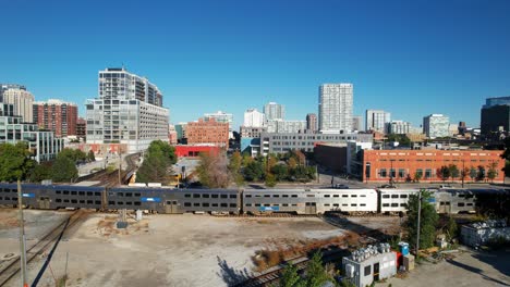 City-Scene-of-Passenger-Train-and-Cars-Passing-Through-Downtown-Drone-View