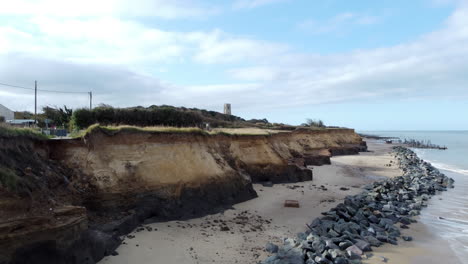 Eine-Luftaufnahme-Erhebt-Sich-Vom-Strand-Und-Zeigt-Die-Beschädigte-Küste-Von-Norfolk.-Die-Küstenerosion-Hat-Eine-Straße-Zerstört-Und-Nahe-Gelegene-Häuser-Bedroht