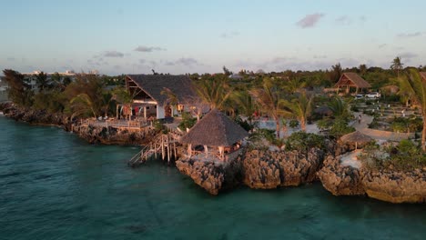 Bathing-tourists-at-beach-bungalow-resort-pool-near-the-Indian-Ocean,-Aerial-rising-pedestal-shot