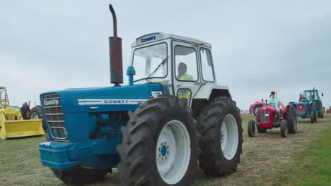 Antique-Tractors-Ford-County-1164-Followed-By-Massey-Ferguson-35-At-The-Parade-During-Great-Trethew-Vintage-Rally-In-Liskeard,-UK