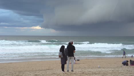 Statische-Aufnahme-Des-Küstenstrandes-Im-Surferparadies,-Dicke-Schicht-Bedrohlicher-Dunkler-Sturmwolken,-Die-über-Den-Himmel-Fegen,-Tobende-Und-Kräftige-Wellen,-Die-Zusammenbrechen-Und-Die-Küste-An-Der-Goldküste,-Queensland,-Treffen