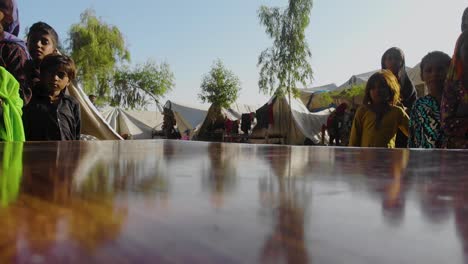 Low-Angle-Table-top-Shot-View-Children-Looking-At-Camera-At-Makeshift-Camps-For-Flood-Disaster-Victims-In-Jacobabad,-Sindh