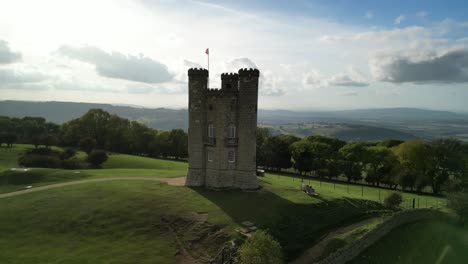 Dramatische-Niedrige-Luftbahnaufnahme-Mit-Linsenflecken-Des-Broadway-Tower,-Ein-Englisches-Wahrzeichen-Stand-Auf-Dem-Beacon-Hill-In-Den-Cotswolds,-Uk