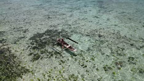 Isleño-Masculino-Remando-En-Canoa-Sobre-La-Laguna-Poco-Profunda-Llena-De-Coral,-Toma-Aérea-Ascendente