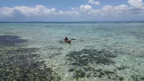 Isleño-Remando-En-Canoa-Sobre-La-Laguna-Poco-Profunda-Llena-De-Coral,-órbita-Aérea-Alrededor-De-La-Toma