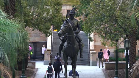 Gerade-Nahaufnahme-Der-Scout-Skulptur-Am-War-Memorial-Anzac-Square-Mit-Menschen,-Die-Zu-Stoßzeiten-Außerhalb-Der-Arbeit-In-Richtung-Hauptbahnhof-Durch-Die-U-Bahn-Gehen,-Brisbane-City