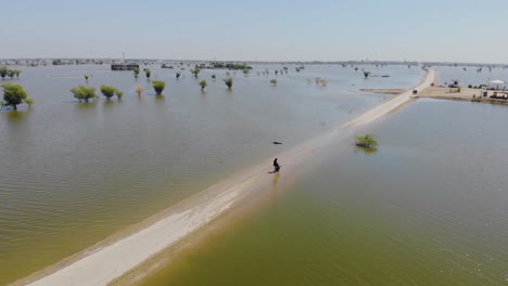 Vista-Aérea-Del-Paisaje-Inundado-En-Maher-Con-Un-Operador-De-Drones-Parado-En-La-única-Carretera-Que-Lo-Atraviesa