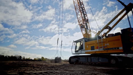 Scenic-aerial-view-of-crane-releasing-a-heavy-material-against-the-ground-on-a-construction-site