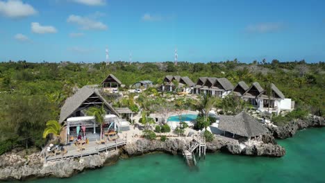 Resort-De-Bungalows-En-La-Playa-Con-Piscina-Y-Gente-Relajándose,-Toma-Aérea-De-Pedestal