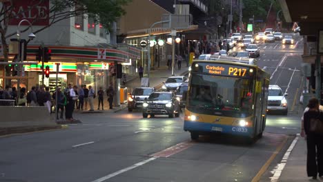 Cars-driving-down-the-slope-on-Edward-street-and-large-crowd-of-pedestrians-crossing-intersection,-peak-hour-traffics-at-downtown-Brisbane-city,-Queensland,-rapid-population-growth,-concerning-issue