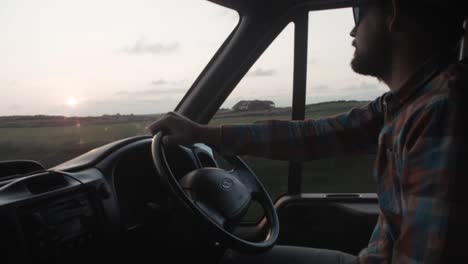 Man-looks-at-golden-hour-sunset-while-driving-van