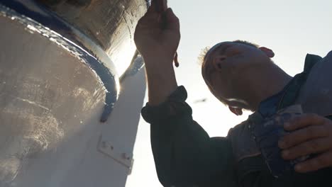 Painter-paints-trim-of-wooden-carvel-built-Greek-fishing-boat-slow-motion-cinematic-low-angle