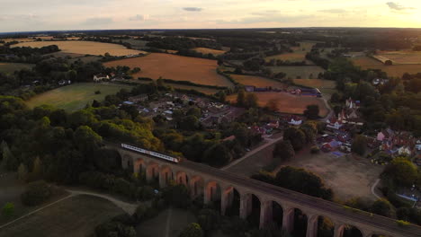 Ein-Zug-Fährt-Bei-Sonnenuntergang-über-Ein-Viadukt-In-Chapel,-Essex