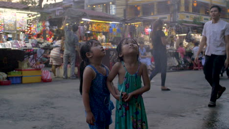 Jóvenes-Asiáticas-Se-Paran-Bajo-El-Aspersor-Y-Sonríen---En-La-Calle-En-Vietnam