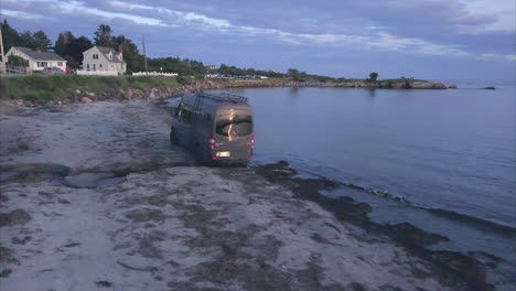 Mercedes-travel-van-crossing-a-small-stream-on-Kettle-Cove-Beach,-Maine