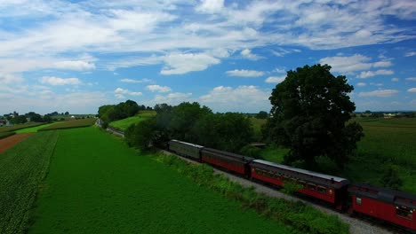 Steam-Train-Puffing-along-Amish-FarmLand-on-a-Sunny-Summer-Day-as-seen-by-a-Drone