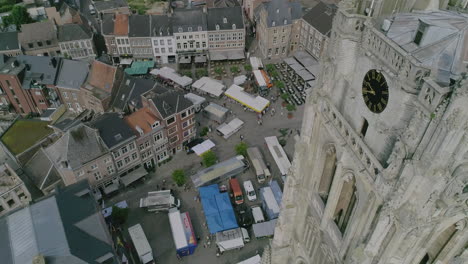 AERIAL:-A-market-on-a-church-square-in-the-centre-of-the-city-with-a-view-on-the-city's-basilica