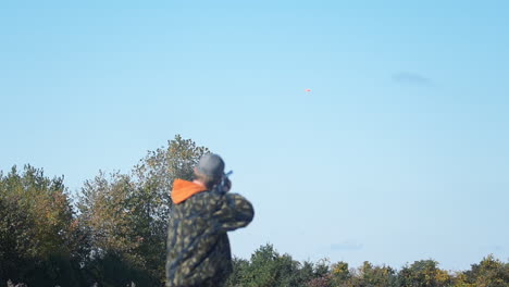 En-Un-Campo-De-Tiro,-Un-Hombre-Apuntando-A-Un-Objetivo-Volador-Con-Un-Rifle,-Disparando-Una-Ronda,-Pero-Fallando