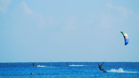 Three-kite-surfers-gliding-across-the-beautiful-blue-ocean-in-Bonaire,-Caribbean